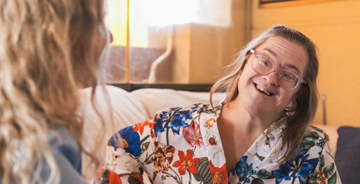 oudere vrouw met downsyndroom op een bank in gesprek met een begeleider