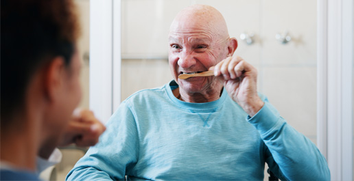 man met beperking poetst tanden, zijn begeleider kijkt toe
