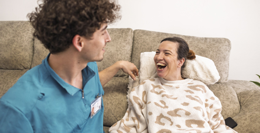 een cliënt met (Z)EVMB op de bank met begeleider, ze lachen samen