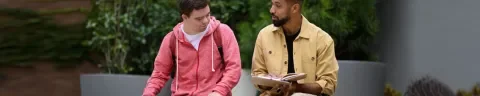 Jongen met verstandelijke beperking in gesprek met begeleider die een notitiblokje in zijn hand heeft
