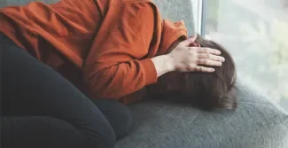 jongere die in foeteshouding op een bank ligt met handen op het hoofd